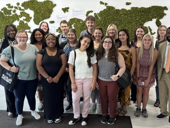 A group of students standing in front of a world map. 